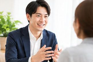 保護者と向き合い笑顔で話を聞く男性の相談員